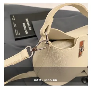 Close-up of premium silver metal hooks and pebble grain leather texture on off-white bag