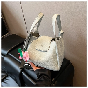 Detail of light blue lychee pattern leather handbag with pink elephant charm and brand logo