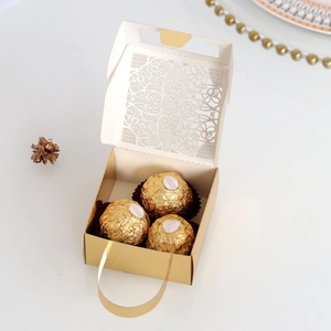 Detailed view of laser-cut gold wedding favor box with sweets and elegant handle