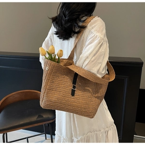 Detail of bohemian straw tote bag with black leather buckle and fine woven texture