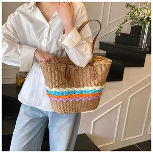 Detail of hand-woven straw tote bag showing colorful stripes and premium brown leather straps