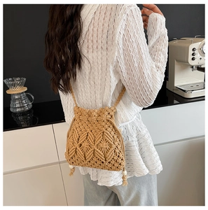Detail of straw woven bucket bag with fringe tassels and hand-woven diamond textures