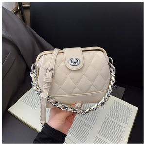Macro detail of beige quilted leather crossbody bag with silver twist lock and chain