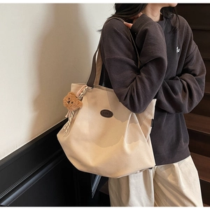 Détail du grand cabas en toile beige avec badge en cuir brun et breloque ours en peluche