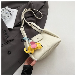 Detailed view of cream textured leather bucket bag with cute yellow elephant charm