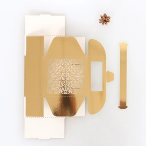 Macro view of laser-cut hollow lace candy box with gold metallic mandala pattern