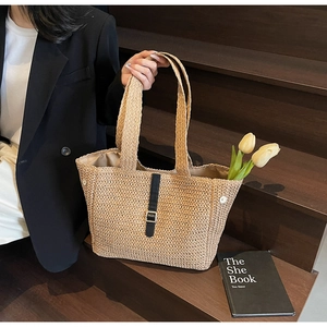 Détail du sac cabas en paille avec texture tissée et lanière en cuir à boucle métal