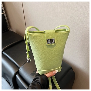 Detail of lime green bucket bag featuring pebbled leather texture and silver buckle