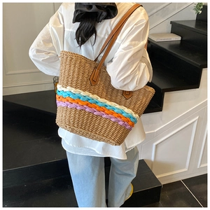 Detailed back view of a large straw tote bag with vibrant colored stripes on a model