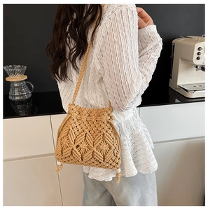 Detail of khaki woven bucket bag with tassel drawstrings and braided shoulder strap