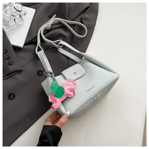 Detail of mint green lychee grain leather bucket bag with cute elephant pendant