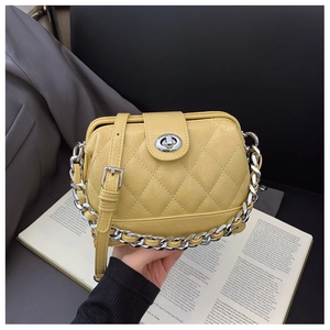 Detail of quilted yellow leather crossbody bag with silver twist lock and metal chain