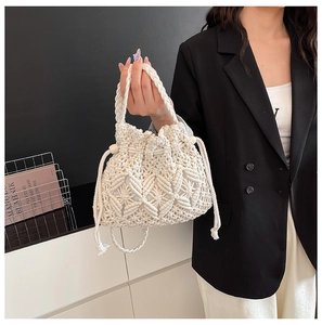 Detail of white hand-woven straw bucket bag with drawstring and decorative wooden beads