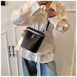 Detail of black lychee grain bucket bag featuring a silver swivel lock and doll pendant