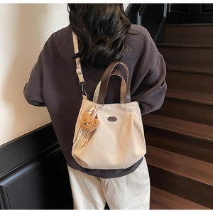 Détail du sac cabas en toile avec anses en cuir marron et pendentif ours en peluche