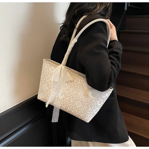 Close-up of cream white jacquard bucket bag with retro geometric patterns and lace bow