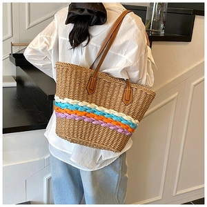 Detail of colorful hand-woven stripes and leather strap on a summer straw tote bag