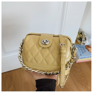 Detail of ginger yellow quilted crossbody bag with silver twist lock and chain strap