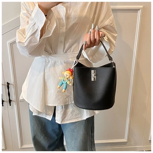 Close-up of black bucket bag with lychee texture, silver twist lock and cute doll charm