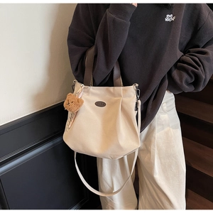 Détail du sac fourre-tout en toile crème avec poignées en cuir et charm ours mignon