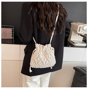 Macro shot of beige macrame woven bucket bag featuring diamond patterns and fringe details