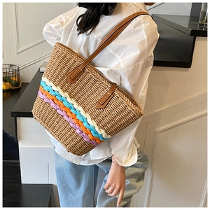 Detail view of woven straw tote bag featuring blue orange stripes and leather straps