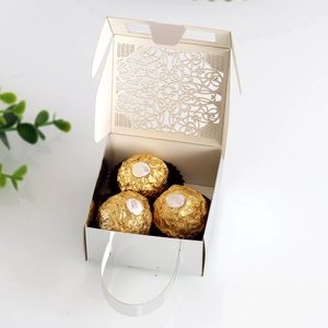 Macro shot of white laser-cut floral lace wedding favor box with handle for chocolates
