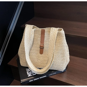 Macro shot of beige woven tote bag with brown leather strap and metal buckle on wooden stairs
