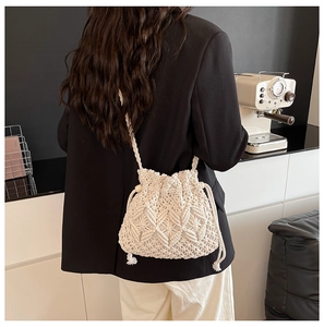 Detail of woven texture and fringe on minimalist bucket bag worn with casual outfit
