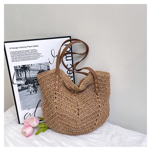 Detail of V-shaped hollow woven straw bag with premium brown leather handles