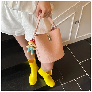 Detail of pink bucket bag featuring lychee texture, gold clasp and cartoon charm