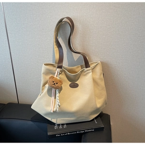 Détail du sac cabas en toile avec anses en cuir marron et pendentif ours en peluche