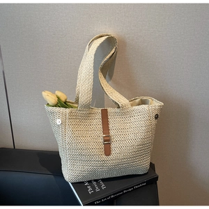 Détail du sac cabas en paille beige avec sangle en cuir marron et boucle en métal