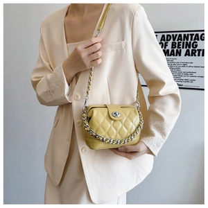 Close-up of bright yellow quilted square bag with silver chain strap and metal lock