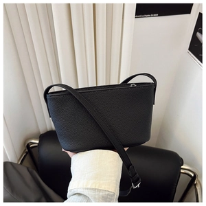 Detail of black lychee grain leather crossbody bag with silver hardware in a chic interior