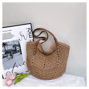 Detail of hand-woven straw tote bag with brown leather straps and V-shape weave pattern