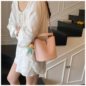 Detailed view of pink leather bucket bag with cute cartoon charm and pearl strap detail