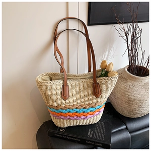 Detailed view of straw woven tote bag with colorful stripes and brown leather straps