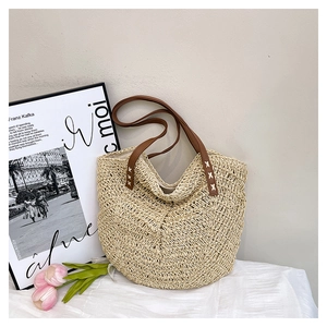 Detail of hand-woven straw texture and brown leather handle with cross-stitching