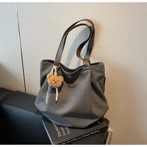Détail du grand sac cabas gris foncé en toile avec anses en cuir brun et pendentif ours