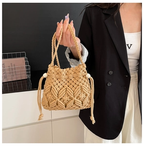 Detailed close-up of handmade woven straw bucket bag with white bead drawstring closure