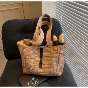 Detailed macro view of straw tote bag showing woven texture, leather strap and metal buckle