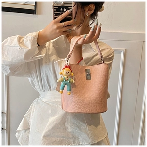 Detail of pink lychee leather bucket bag with silver clasp and cute doll pendant