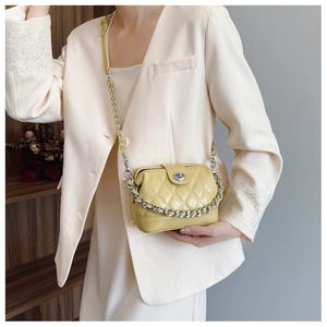 Detail of yellow quilted leather crossbody bag with silver chain and turn-lock closure