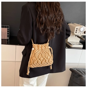 Detail of hand-woven straw bucket bag with hollow geometric patterns and tassel fringe