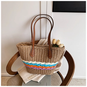 Macro view of woven straw tote bag featuring colorful stripes and leather handles