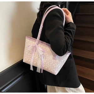 Detail of purple tote bag with geometric patterns, lace bow, and ribbon handle accents