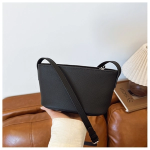 Close-up of black lychee grain leather bucket bag with silver zipper and slim shoulder strap