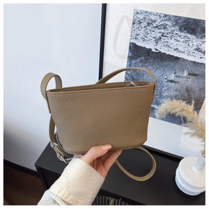 Detail of taupe litchi grain leather bucket bag with metallic zipper and slim shoulder strap