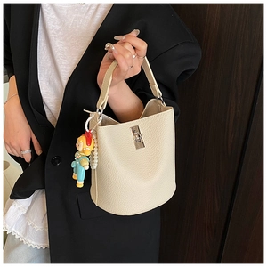 Detail of off-white bucket bag with lychee texture and cute colorful doll pendant